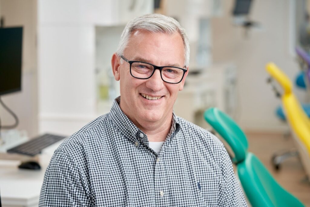 Smiling orthodontist in a dental office, representing TopSmiles Pediatric Dentistry & Orthodontics in Winnipeg, emphasizing orthodontic care and braces for children.